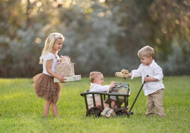 A group of children holding presents in a wheelbarrowDescription automatically generated