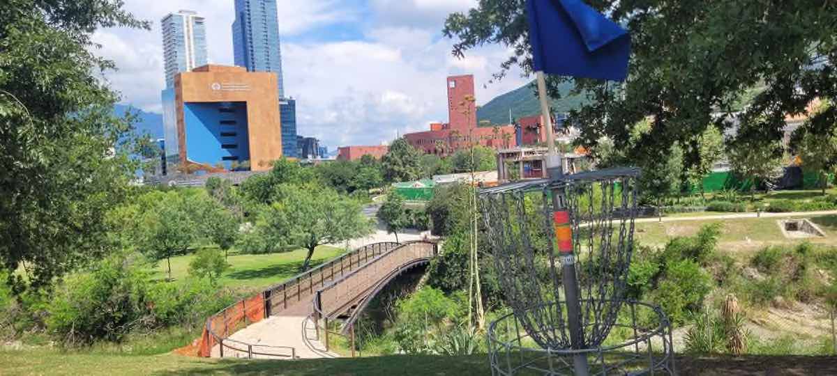 A disc golf basket with a view of a city in the background