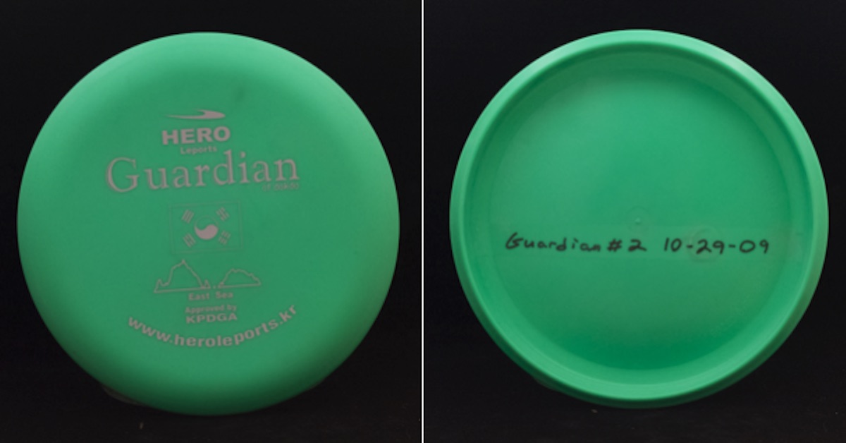 A green disc seen from top and bottom. The top has a samp with the words "Hero" and "Guardian" very prominent