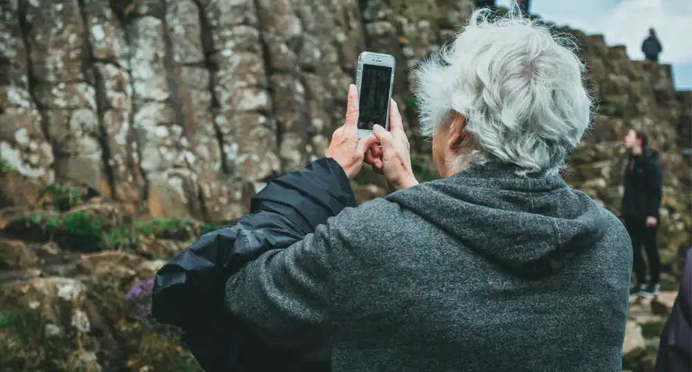 Man takes a picture of the view on his cell phone.