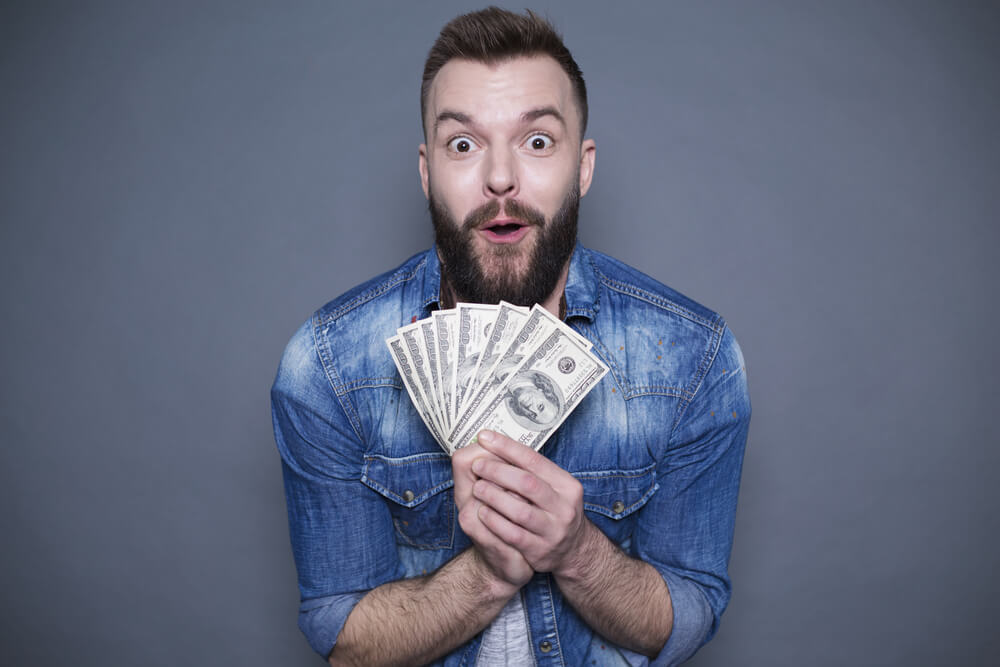 man surprised and holding title loan cash from Tennessee Title Loans, Inc.