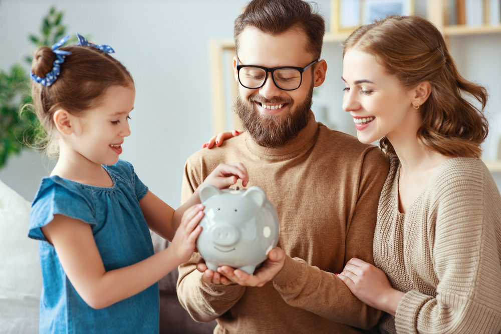 Family putting money away into piggy bank