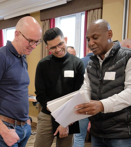 Three Strategic Coach Members discussing entrepreneurial concepts at a workshop