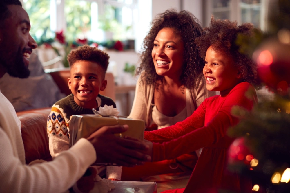 Warmly lit, smiling family exchanging Christmas gifts