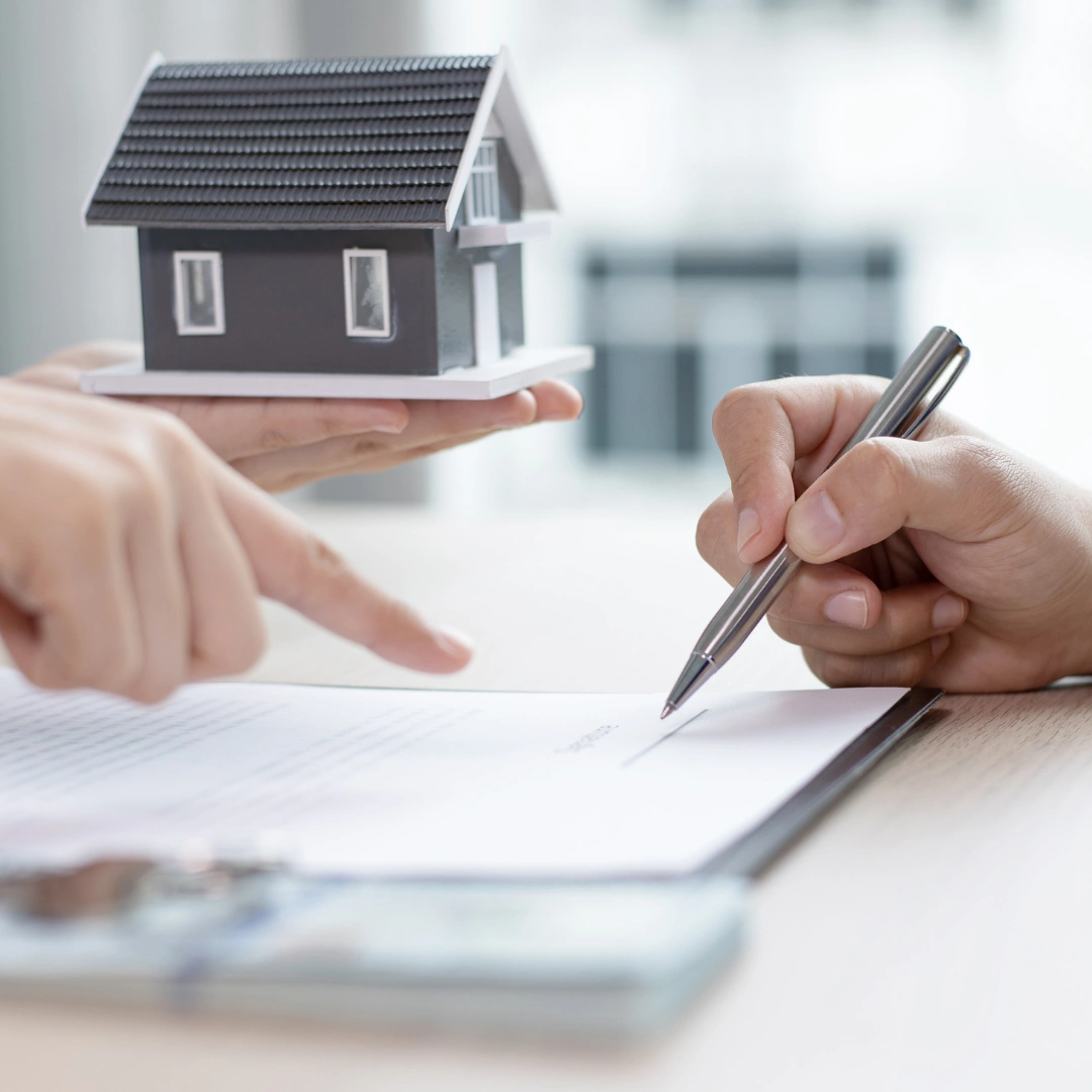 Someone holding a small house while another person writes.