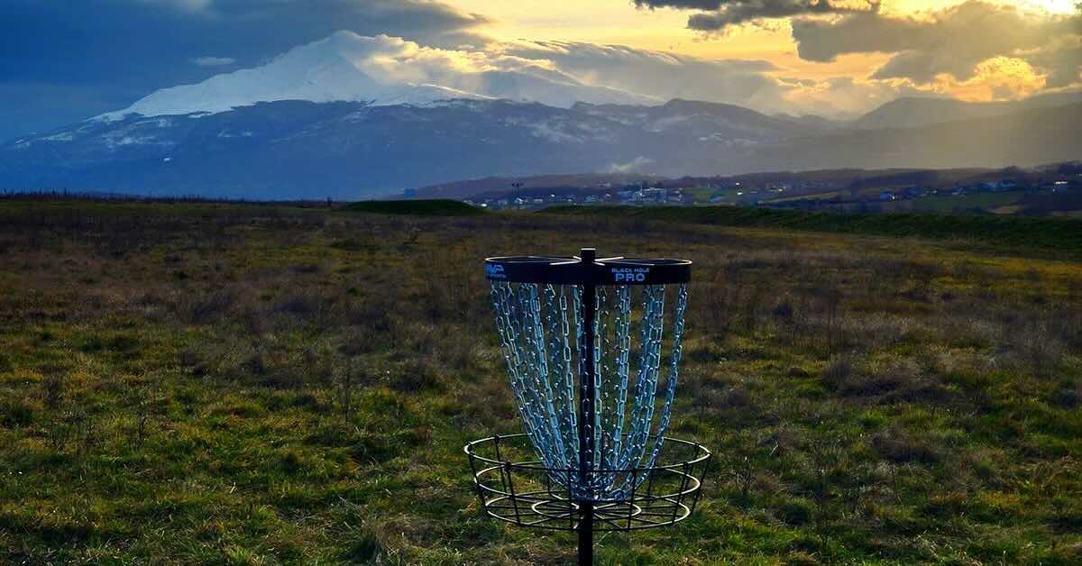 A basket in an open meadow with mountains and a sunset behind