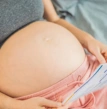 Barriga de mulher grávida lendo uma folha nas mãos