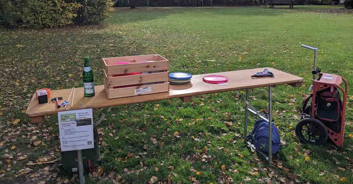 A biergarten table with discs and other items in a park