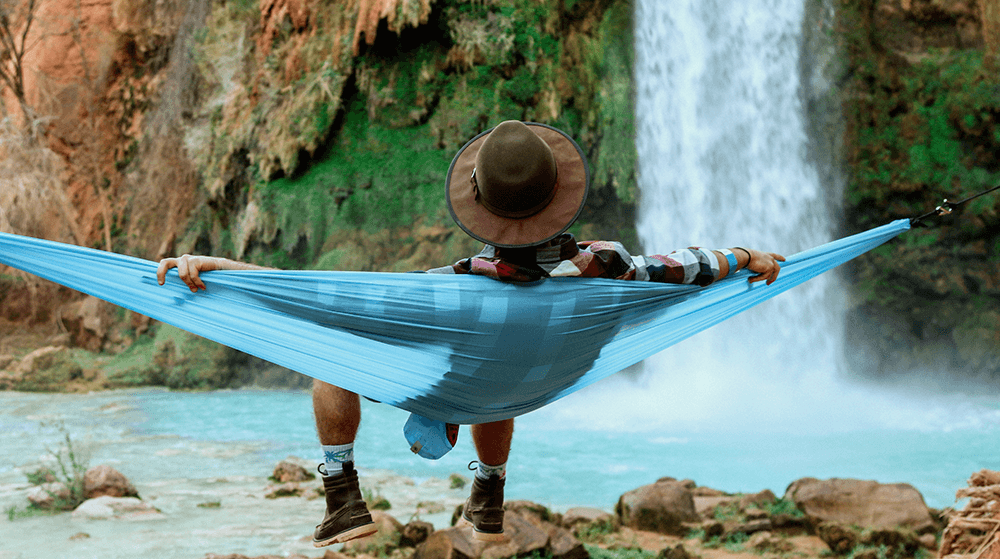 Man on hammock staring at waterfall