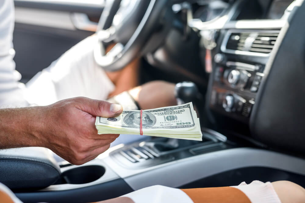 man holding vehicle title loan cash