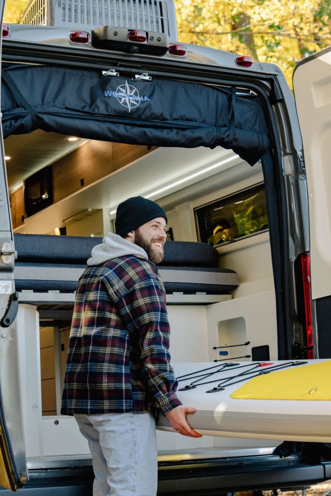 man unloading paddle board from RV