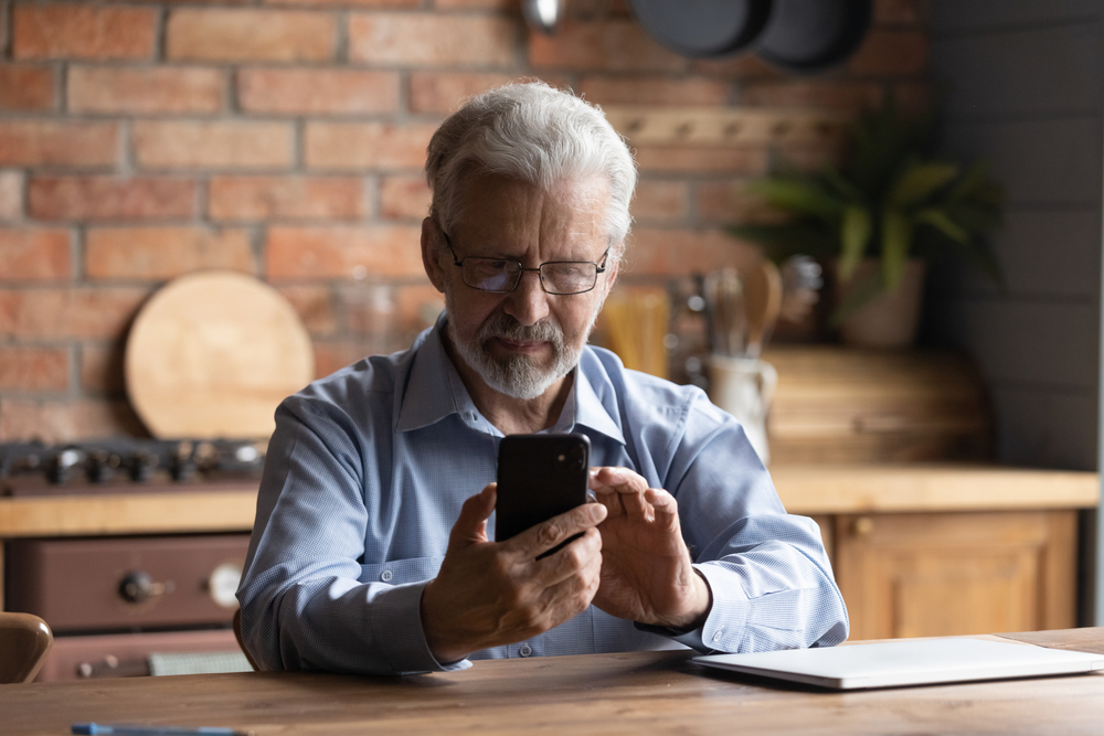 Man doing sums on a phone whilst looking at paperwork