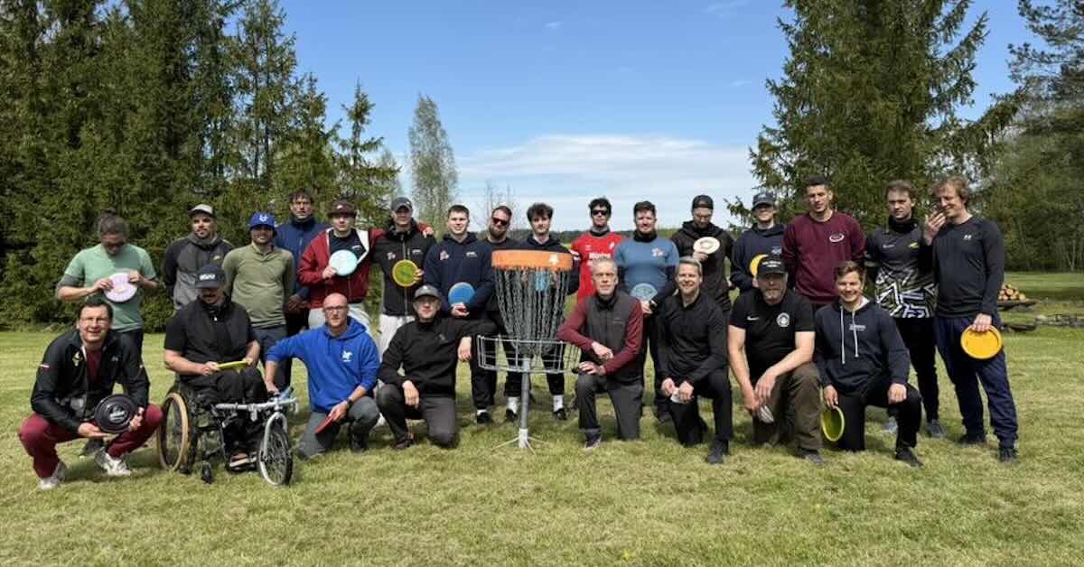 A group of men around a disc golf basket posing for photo