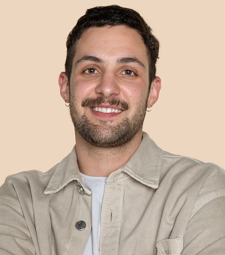 Person smiling in front of a beige background