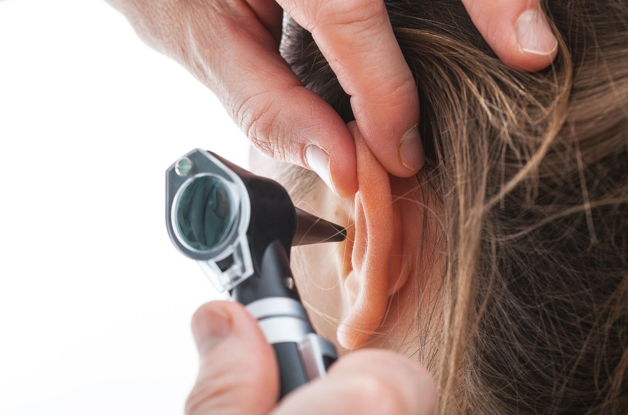 Person examining another person's ear with an otoscope