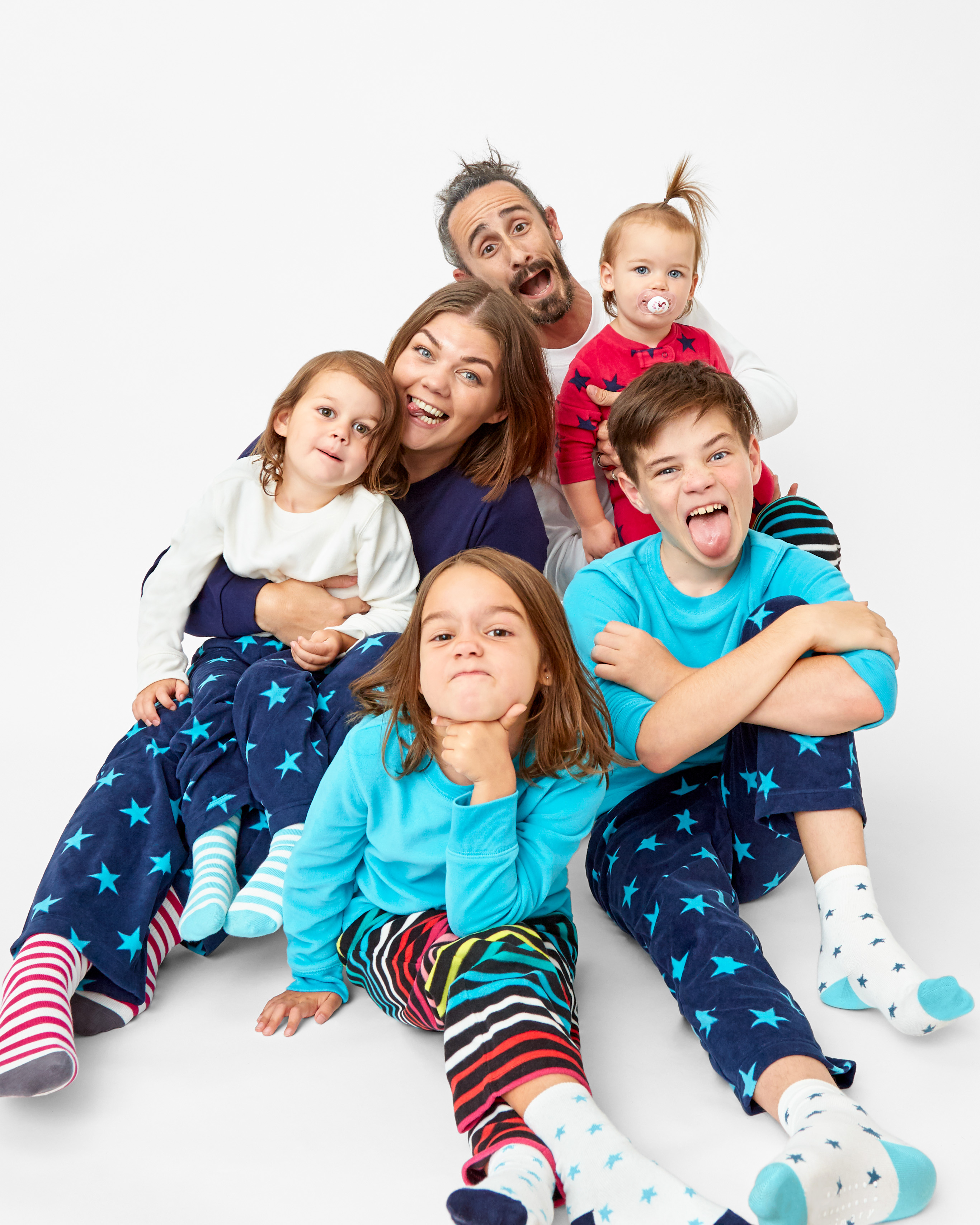 family sitting together wearing matching multicolored fleece pajamas