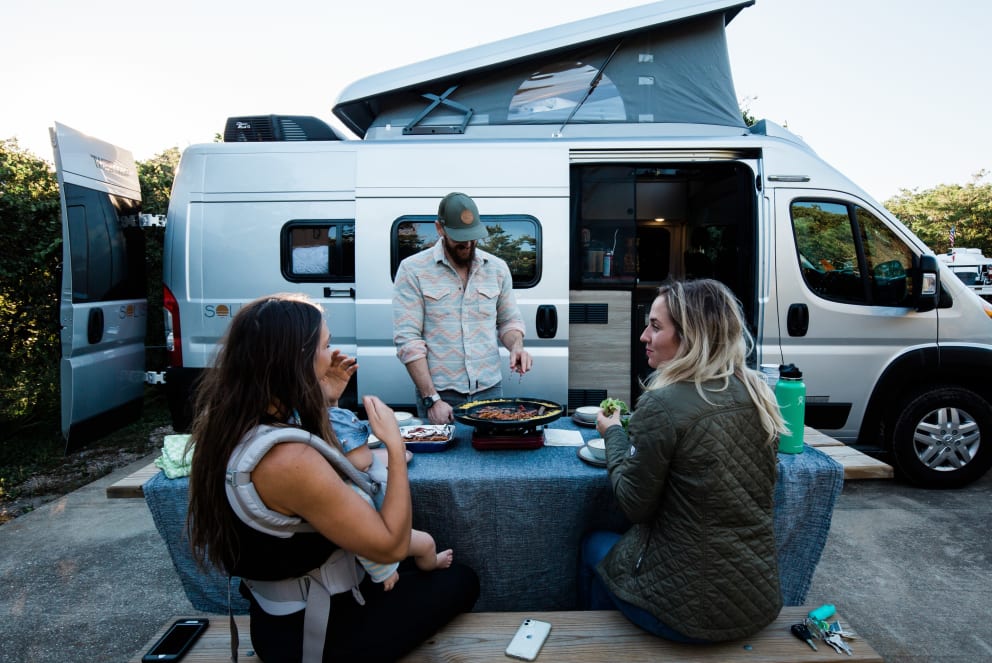 friends eating dinner at campground with rv