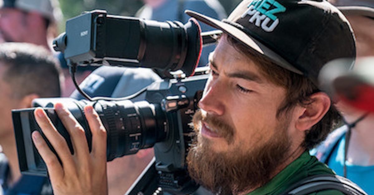 a man with a medium-length beard holds a high-end camera