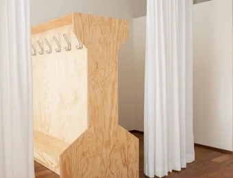 Blick in ein Yoga-Studio mit sichtbarem Teilbereich der Garderobe, inklusive Ablagefächer und Sitzmöglichkeiten, helle und offene Raumgestaltung.