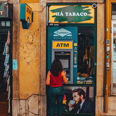 A woman standing in front of a atm machine.