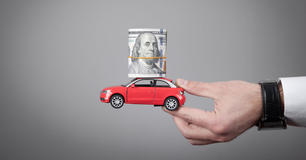 Man holding a toy car with cash