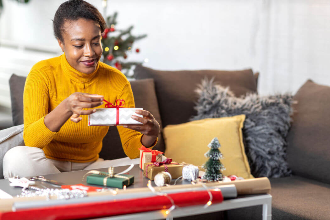 A black woman unwraps a gift after receiving a holiday cash loan.