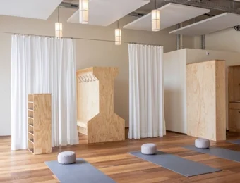 Yoga-Studio mit ausgerollten Yogamatten und bereitgestellten Sitzkissen, offene Raumgestaltung für Gruppen- oder Einzelübungen.