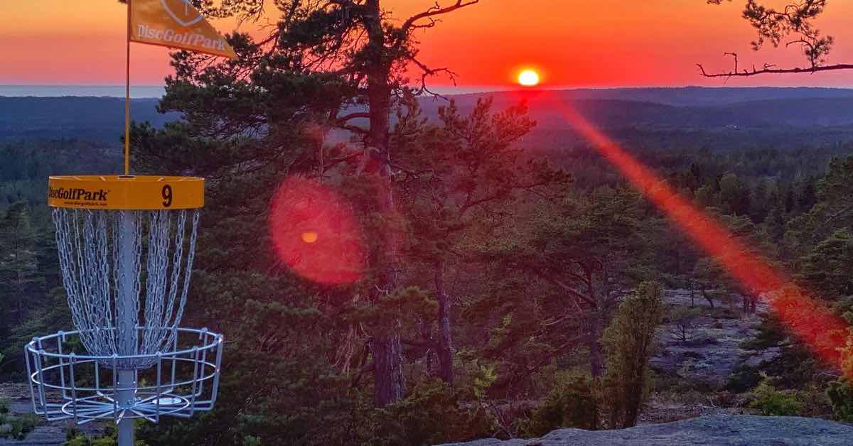 Sunset and a disc golf basket on a rock