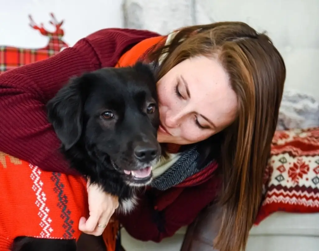 A woman hugs a black dog