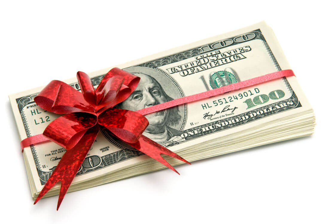 A red bow wrapped around a stack of money represents how to manage your holiday cash flow.