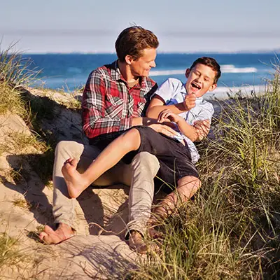 Dad and son wrestling on the beach.