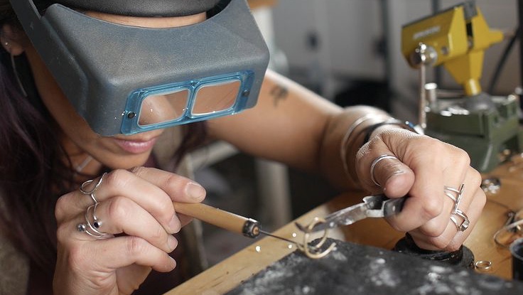woman wearing magnifiers soldering jewelry