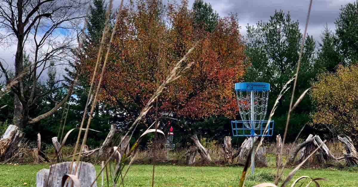 A man putts into a disc golf basket tucked among large boulders