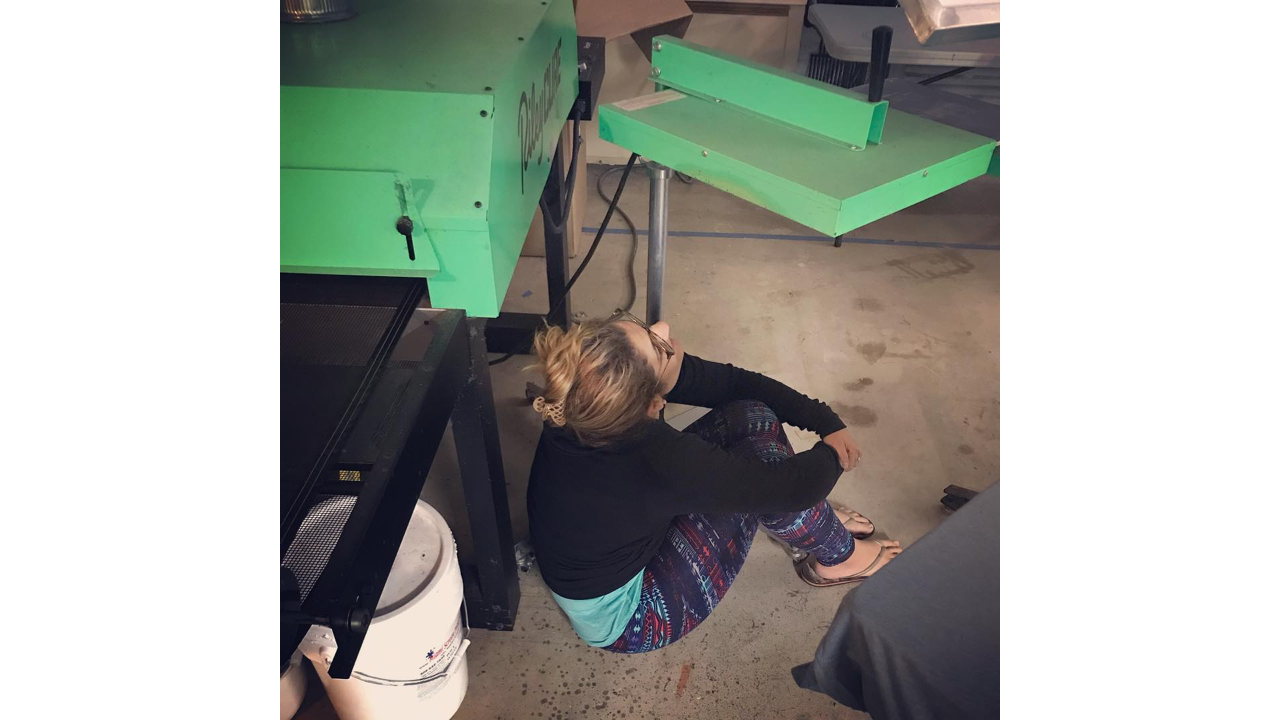 A woman under a flash unit for screen printing.