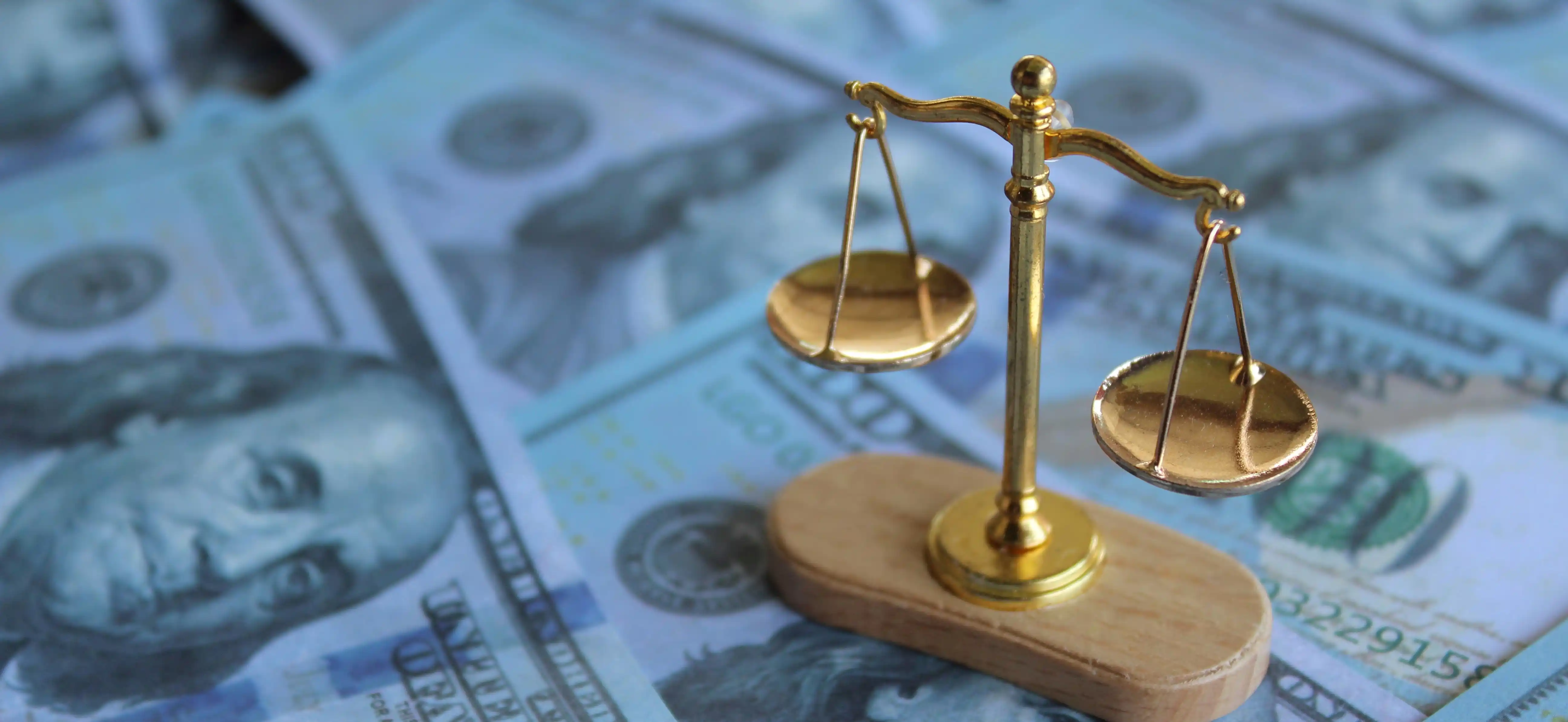 Gold balance scale on US dollar bills representing fair pay model and equitable compensation strategy