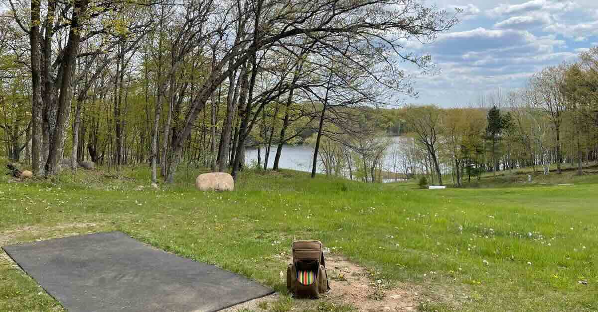 A rubber disc golf tee pad and a view of a lake beyond