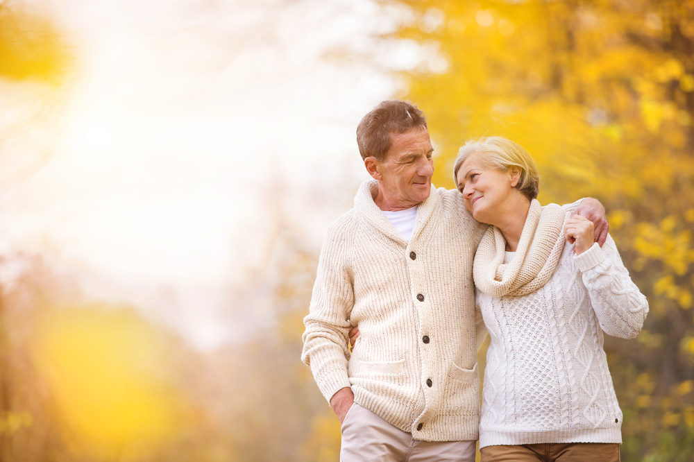 An elderly couple taking a walk in a forest in autumn