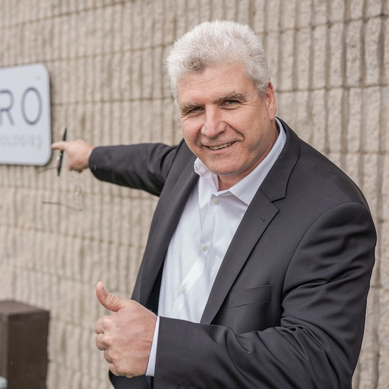 Ofer the CEO pointing to the sign outside the lab