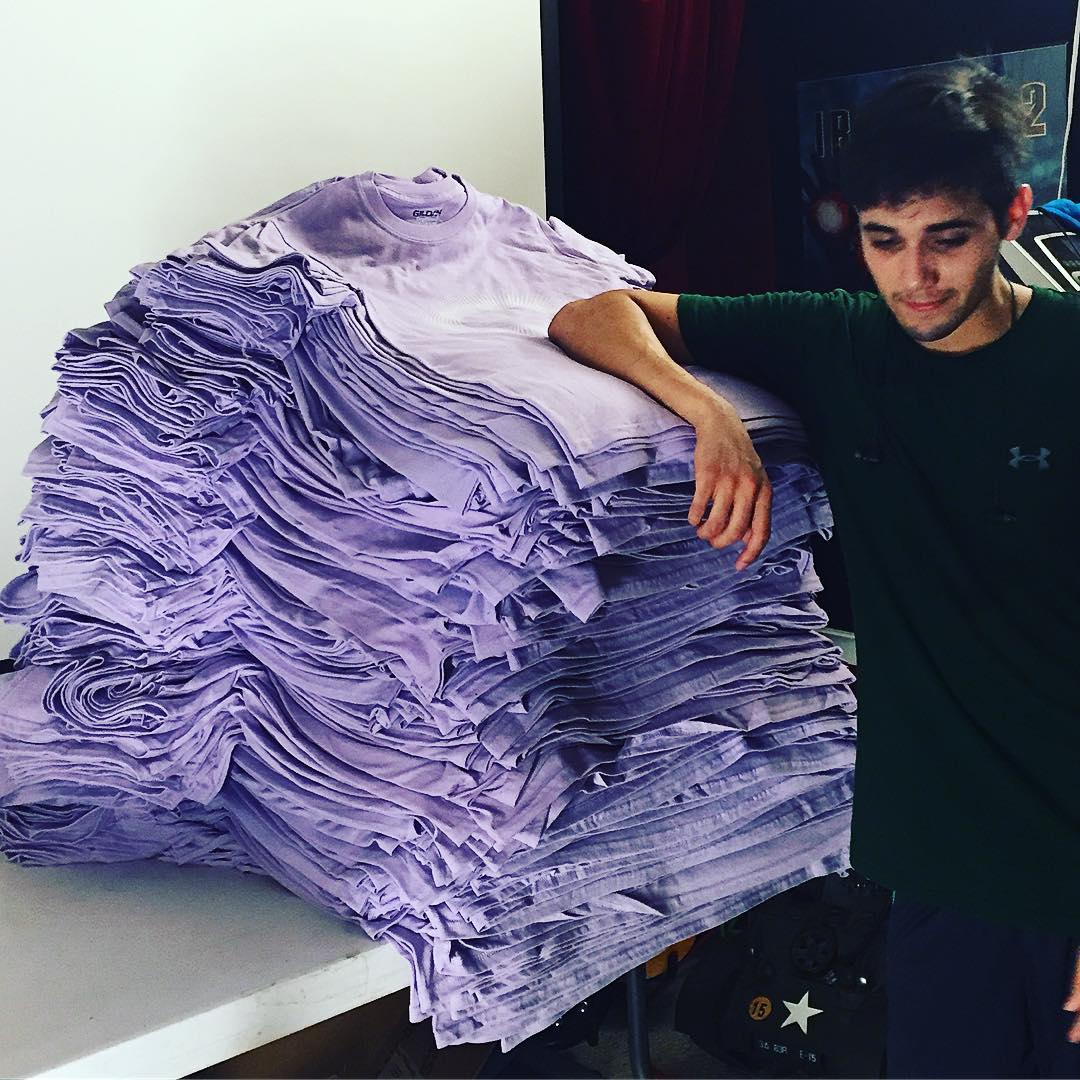 Success Print Shop's owner with a stack of t-shirts