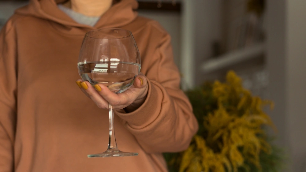 Woman holding wine glass of water