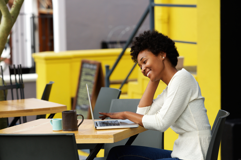 Happy woman using laptop at outdoor coffee shop