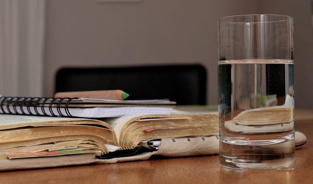 glass of water and notebook sitting on table