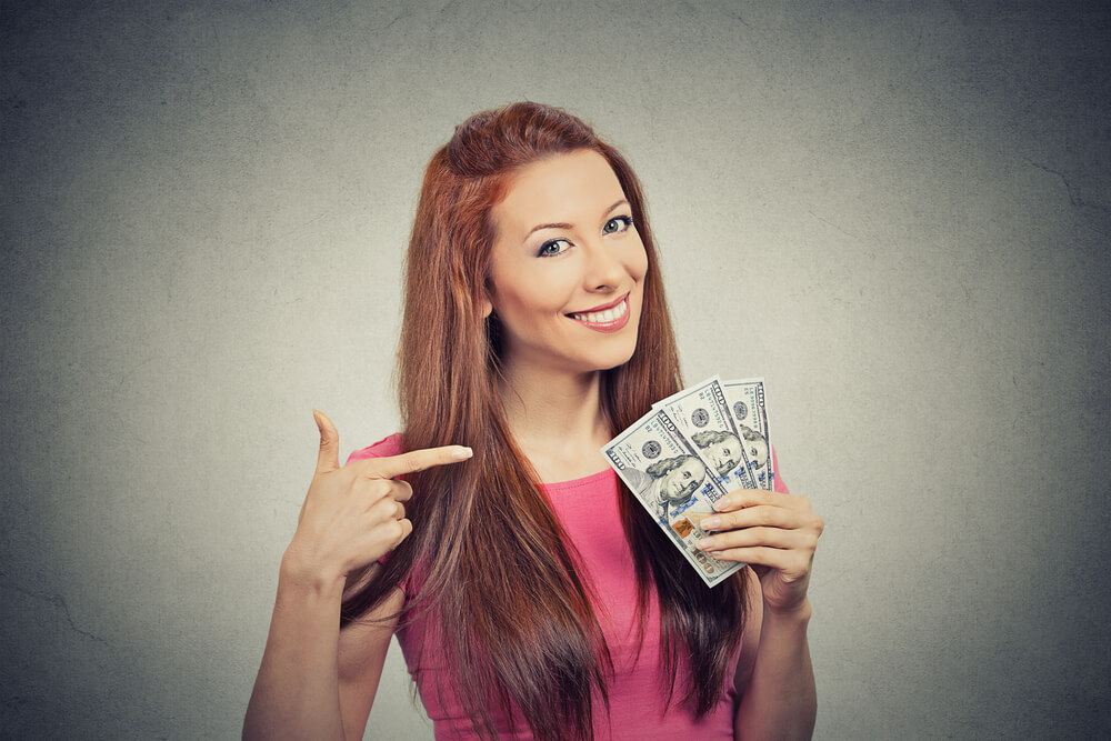 woman smiling and pointing at payday loan cash