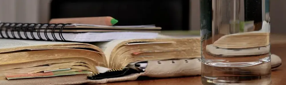 glass of water and notebook sitting on table