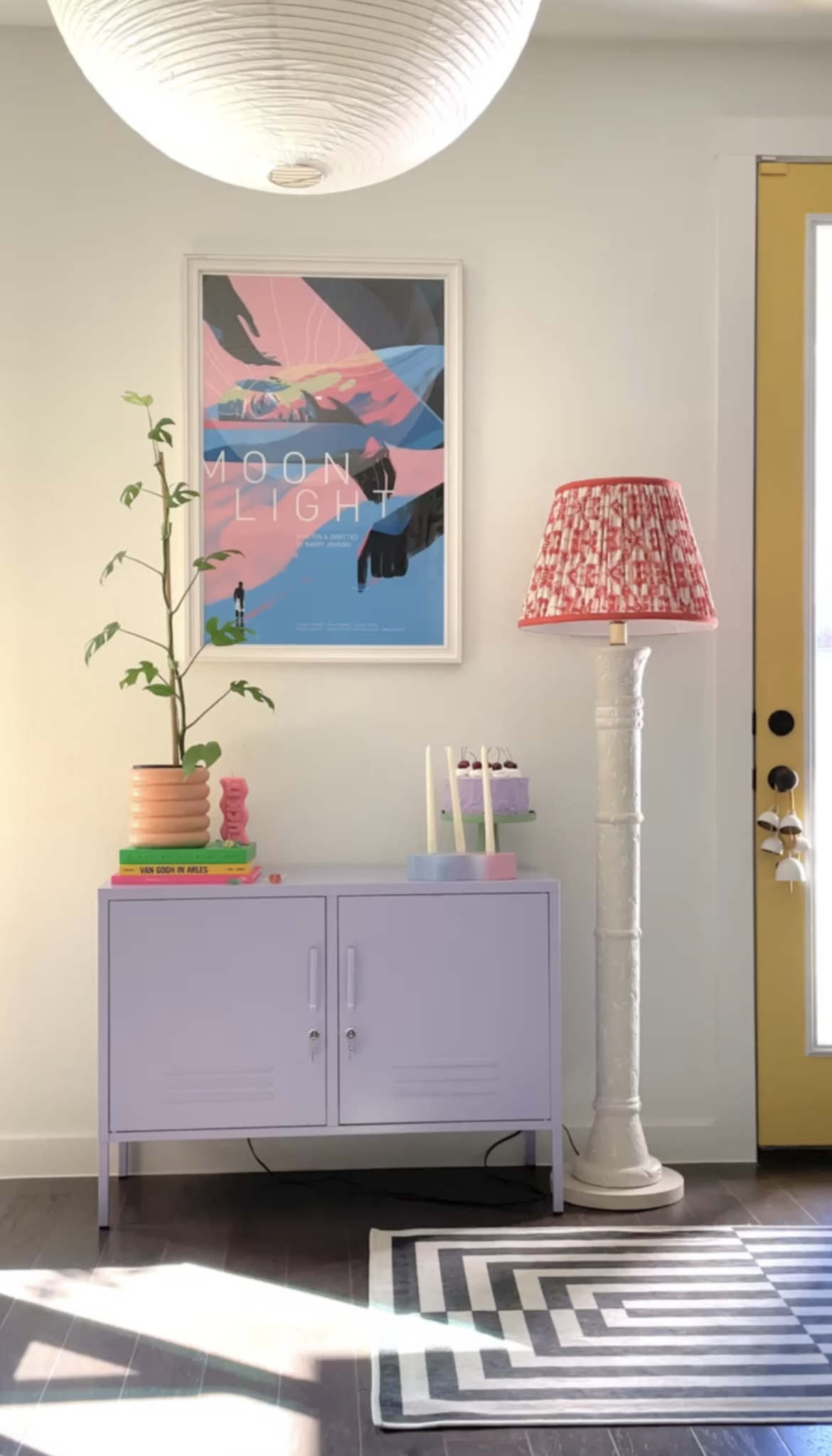 pink poster in white frame over purple book case