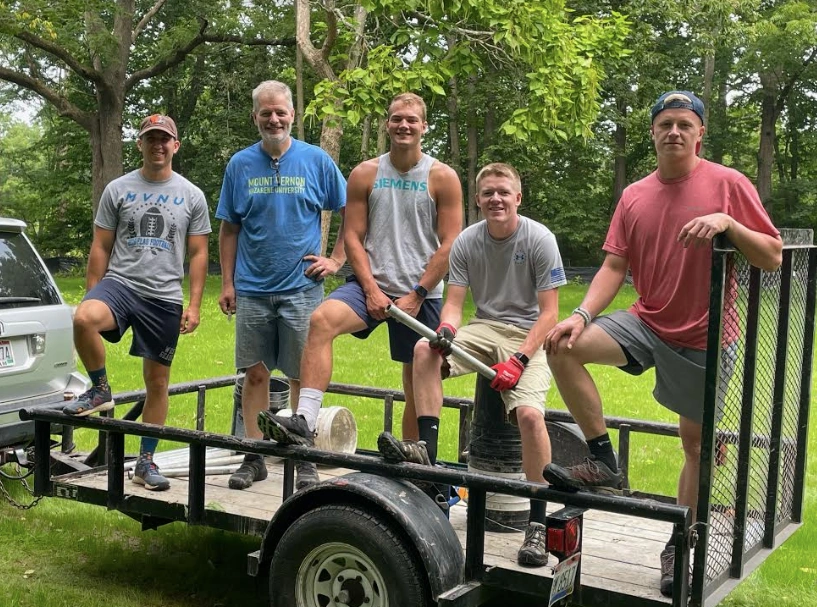 Group of young men on a trailer smiling.