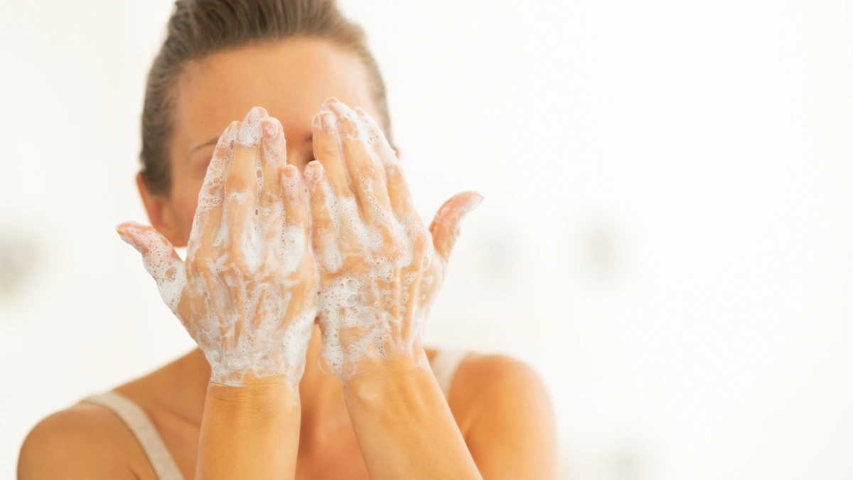 woman washing face with bubbles on hands