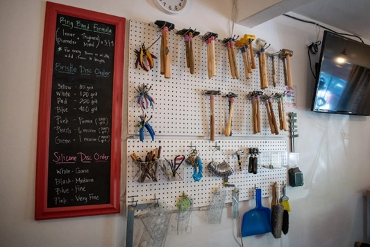 image of a pegboard with jewelry toold like hammers and pliers hanging on it