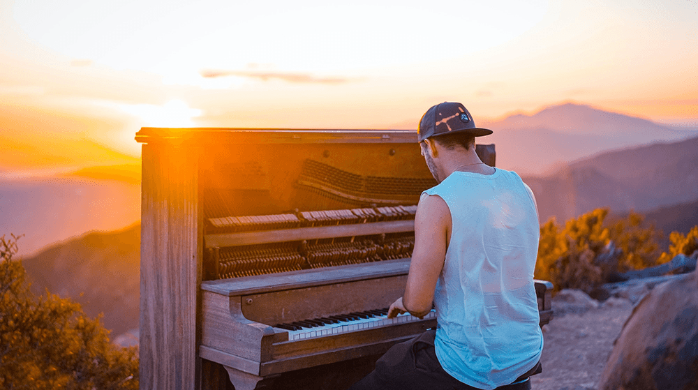Man playing piano on mountain at sunset