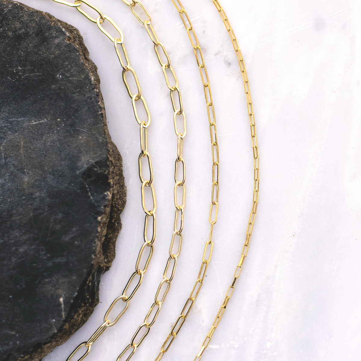 4 gold paper clip chains in decreasing sizes curved around a geode